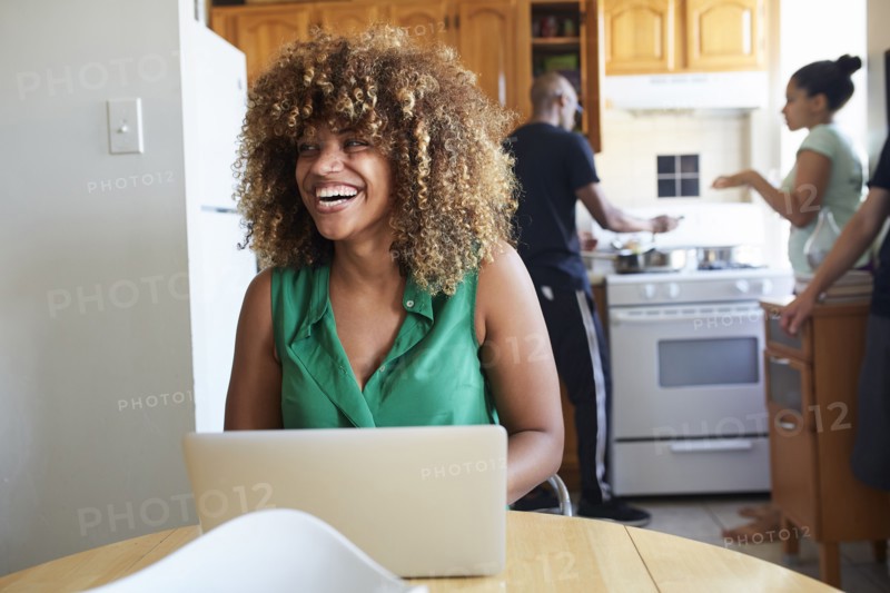 Laughing Black woman using laptop at table