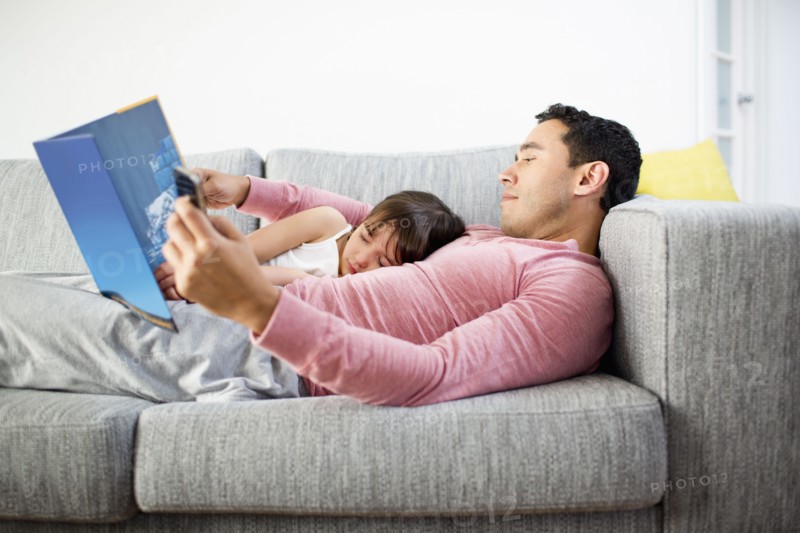 Father and daughter reading together on sofa