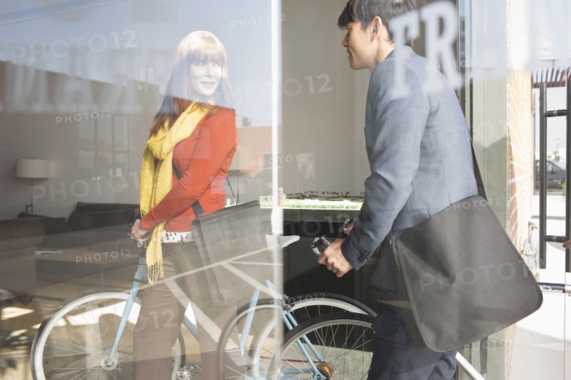 Business people wheeling bicycles in office