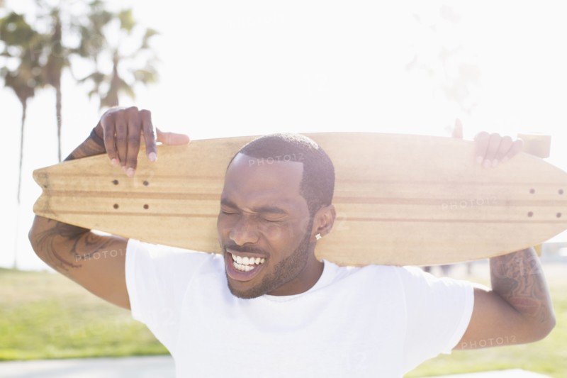 African American man carrying skateboard outdoors