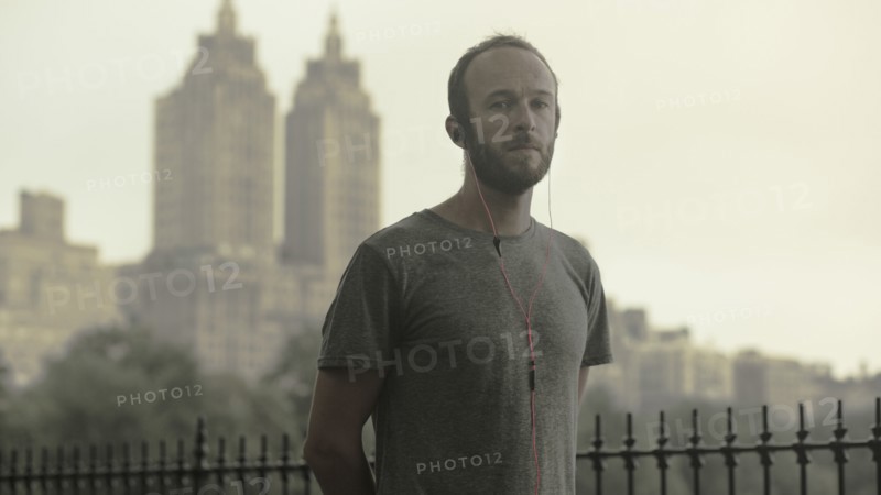 Caucasian runner listening to earbuds in front of city skyline