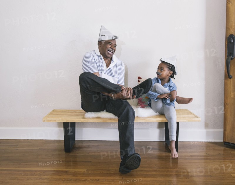 African American grandfather and granddaughter playing on bench