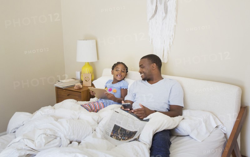 African American father and daughter sitting on bed