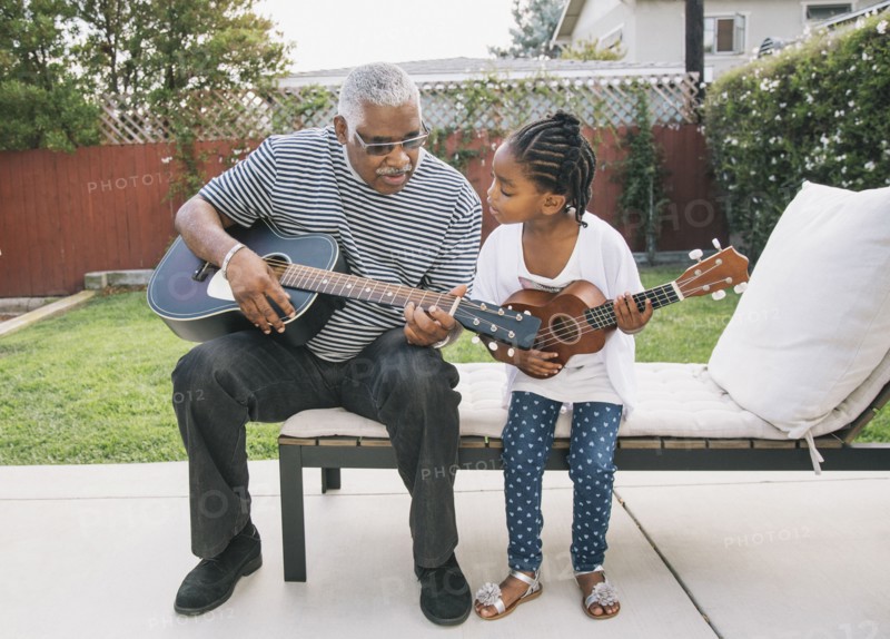 African American grandfather teaching granddaughter to play guitar
