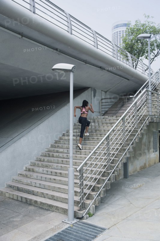Mixed Race woman running up urban staircase
