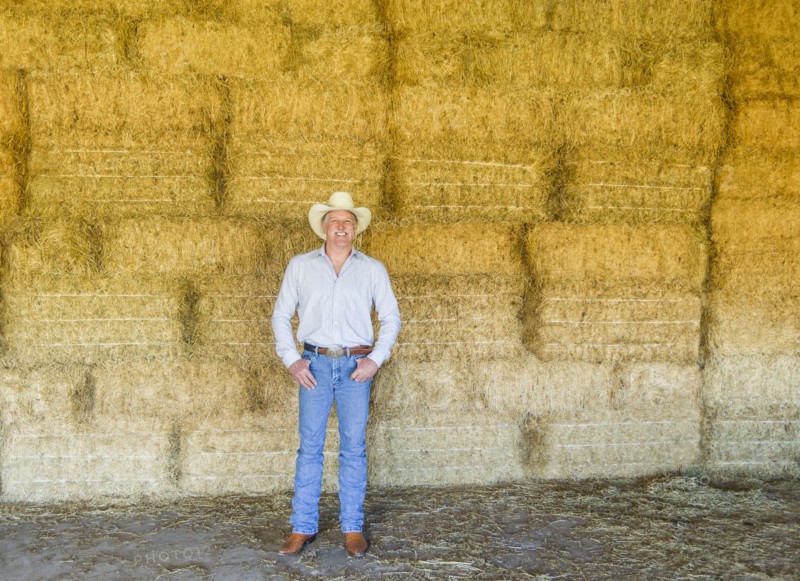 Caucasian farmer standing with hay bales