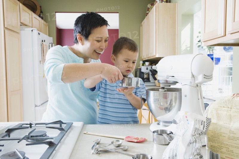 Asian mother and young son baking in kitchen