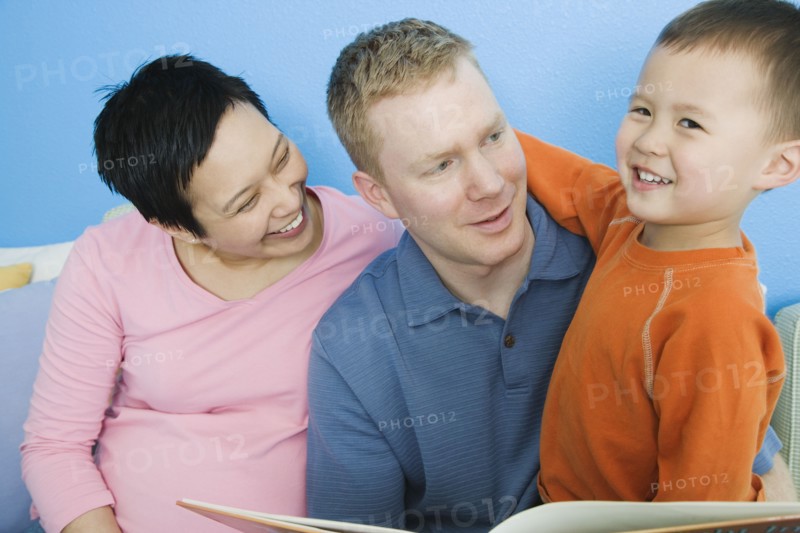 Pregnant parents reading to young son