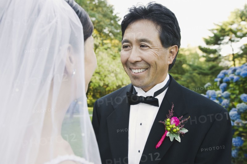 Asian groom smiling at bride