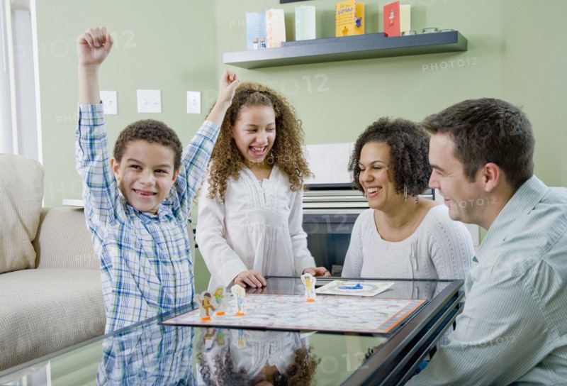 Mixed race family playing board game