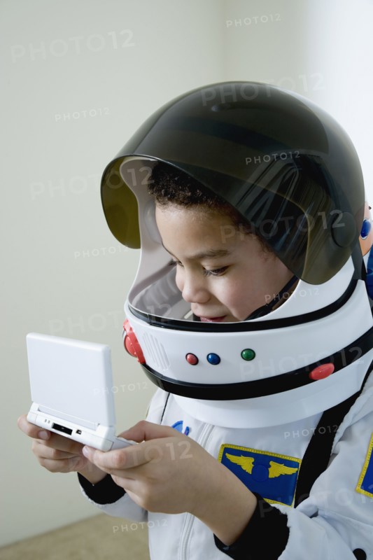 Mixed race boy in astronaut costume with video game