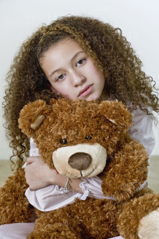 Mixed race girl in nightgown with teddy bear