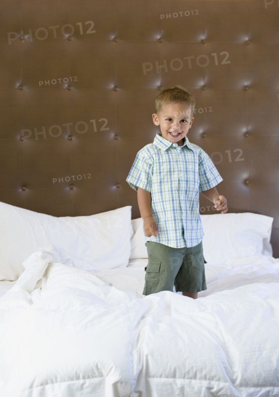 Mixed race boy jumping on bed