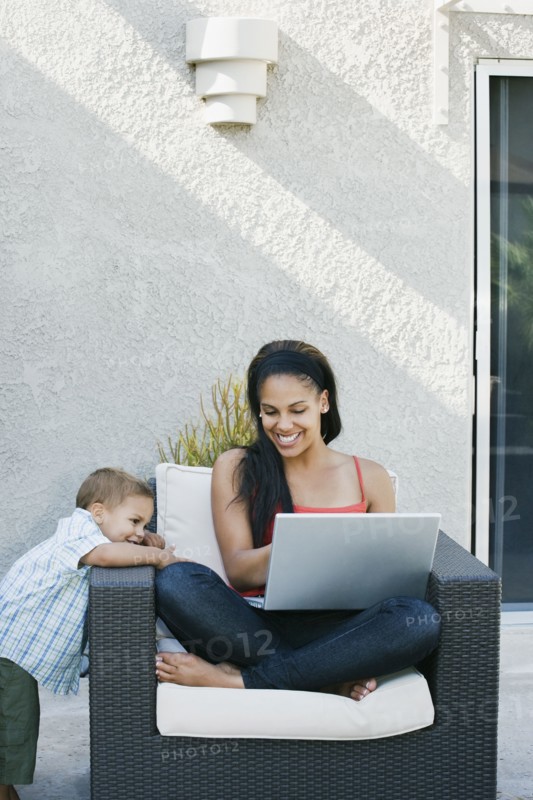 Mother and son looking at laptop on patio