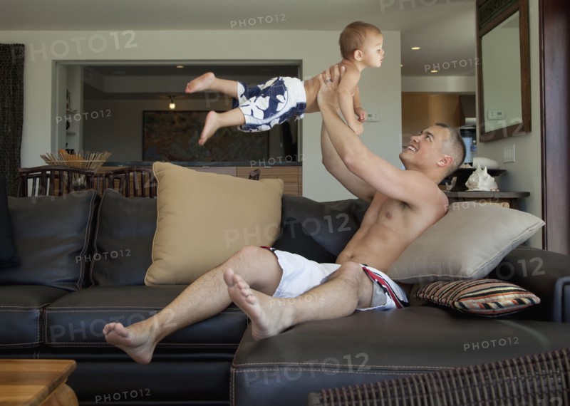 Father lifting son in living room