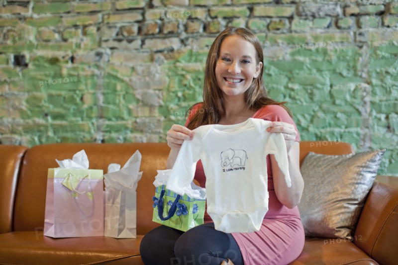 Pregnant Caucasian woman opening baby shower gifts