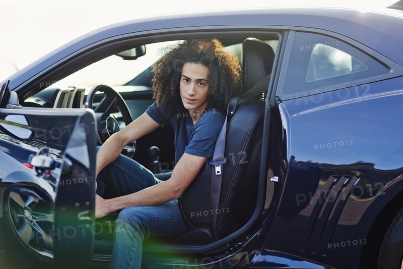 Mixed race teenager sitting in car