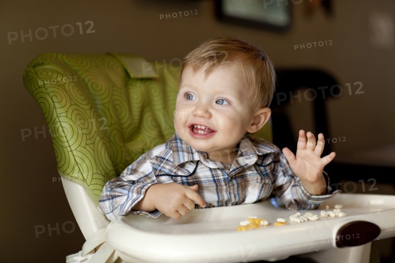 Caucasian boy eating in high chair