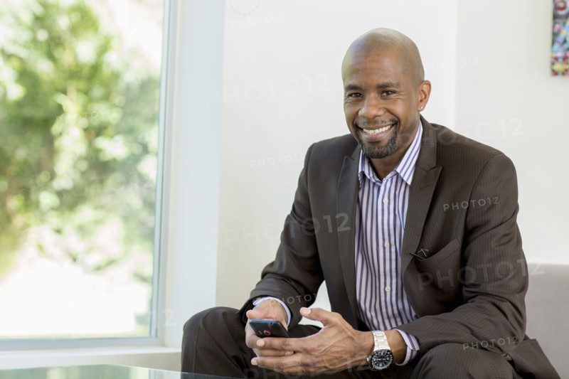 Black businessman text messaging on cell phone