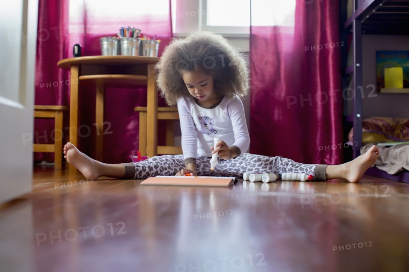 Mixed race girl sitting on floor drawing