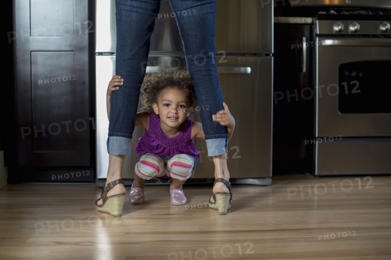 Mixed race girl playing underneath mother's legs