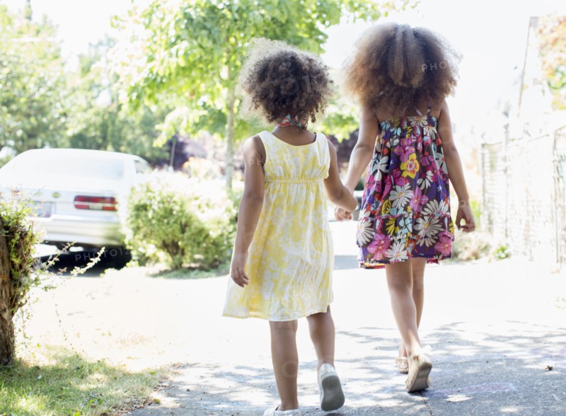 Mixed race sisters holding hands