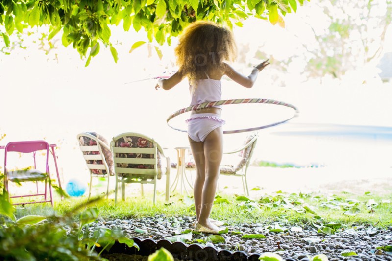 Mixed race girl twirling plastic hoop