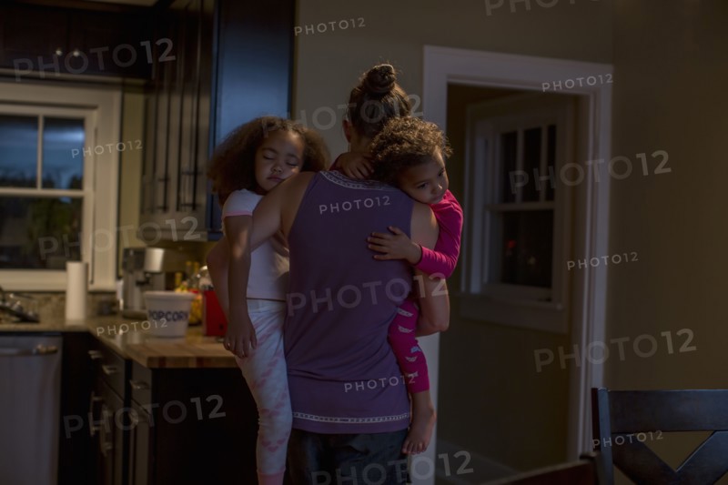 Mother carrying sleeping daughters