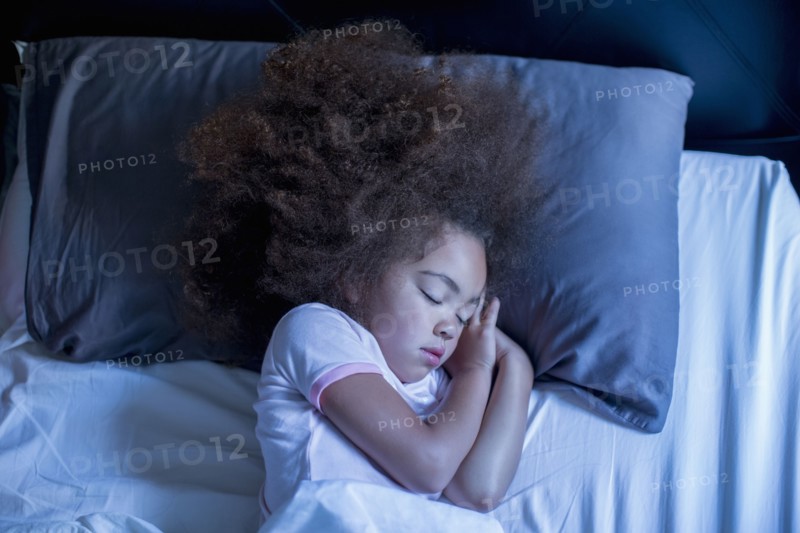 Mixed race girl sleeping in bed