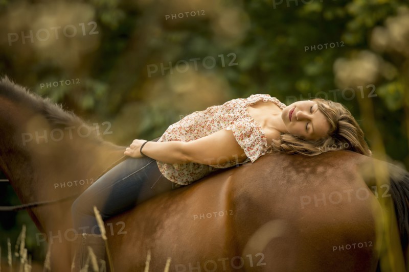 Caucasian woman laying on horse in pen