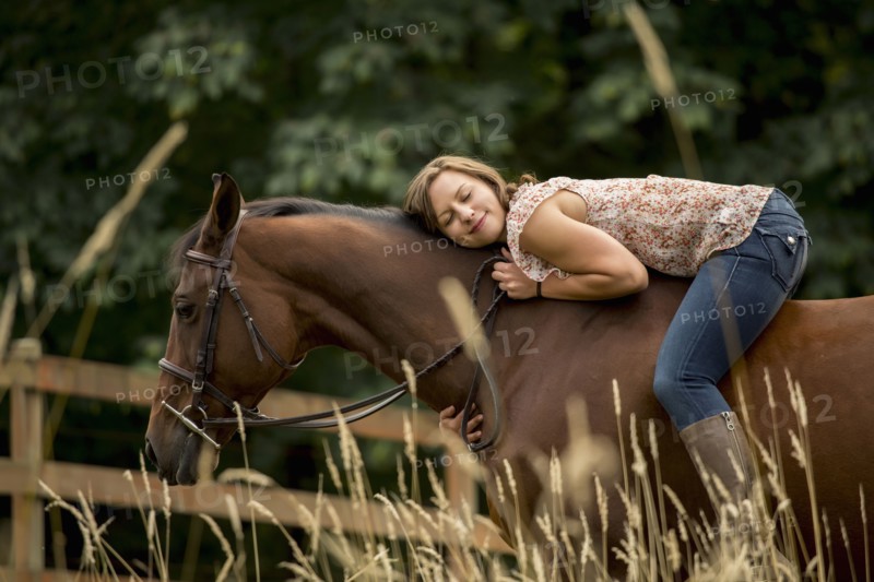 Caucasian woman laying on horse in pen