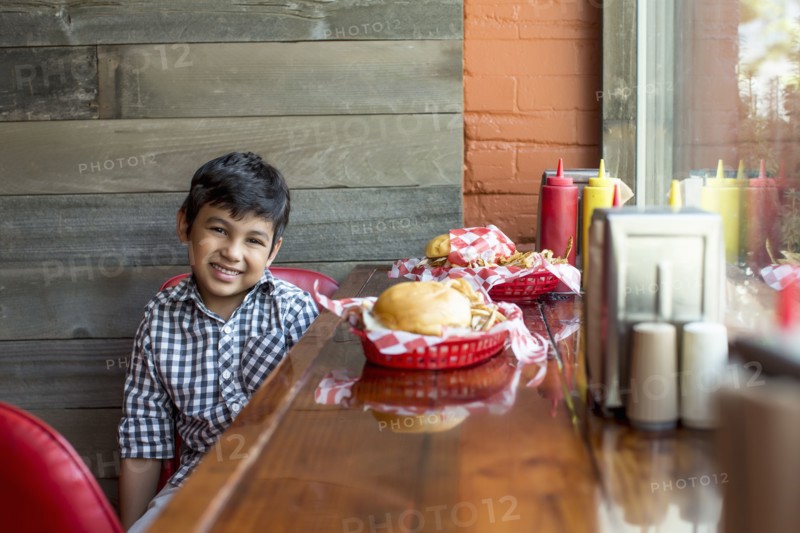 Mixed race boy having burgers in restaurant