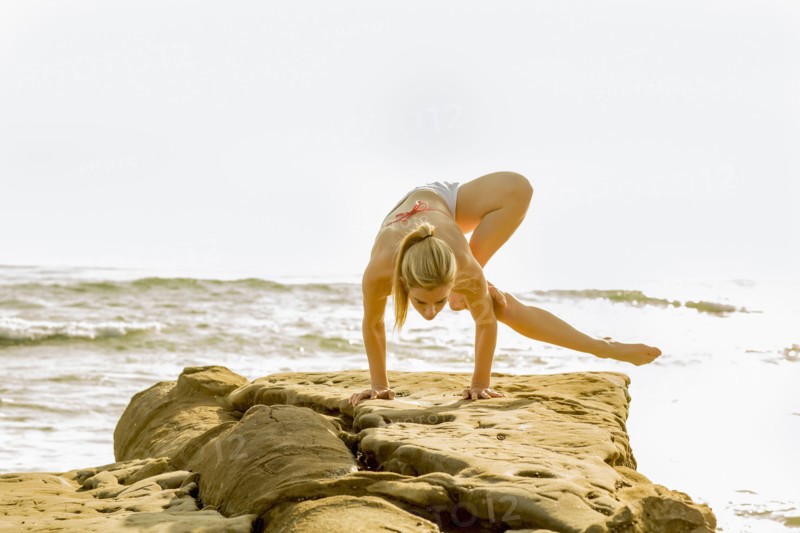 Caucasian woman practicing yoga on rocky beach