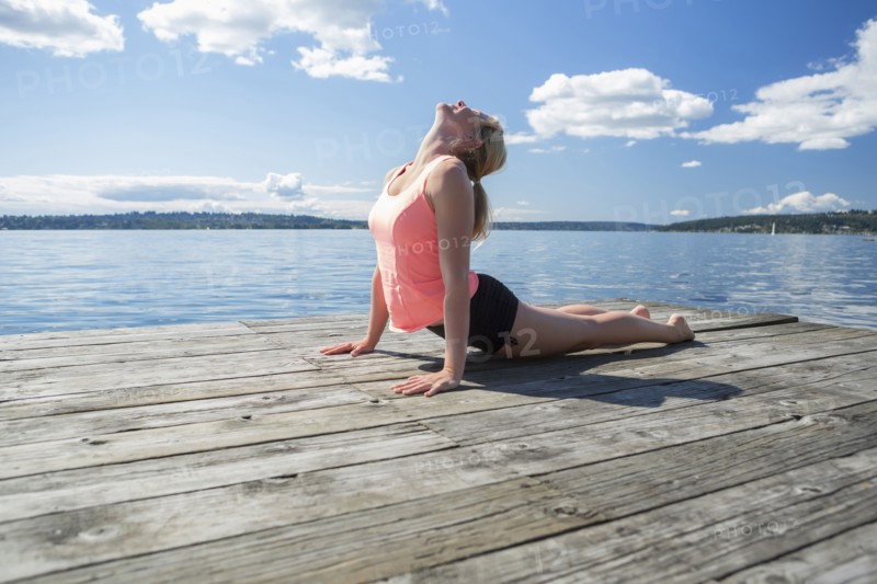 Caucasian woman practicing yoga on wooden dock