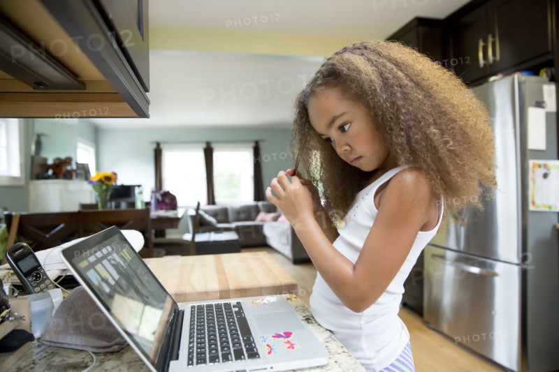 Mixed race girl using laptop in kitchen