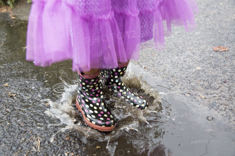 Mixed race girl playing in puddle