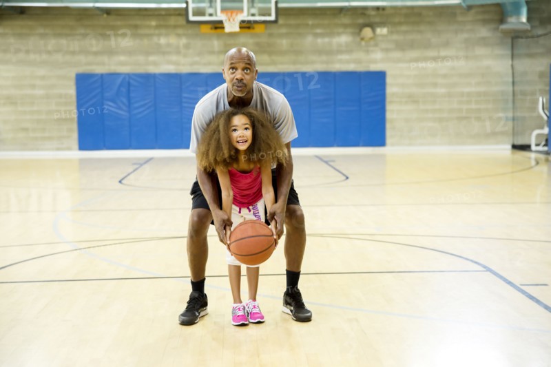 Father and daughter playing on basketball court
