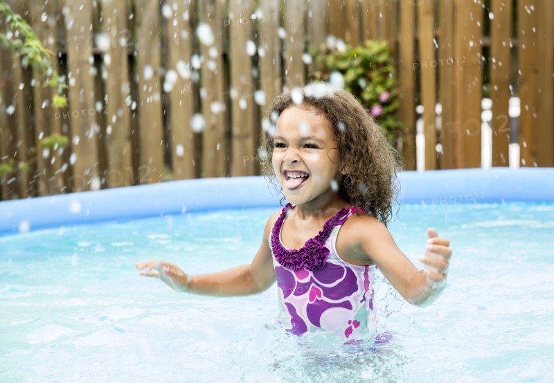 Mixed race girl splashing in swimming pool