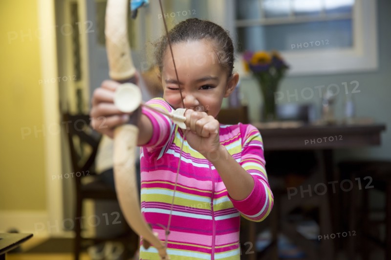 Mixed race girl playing with bow and arrow