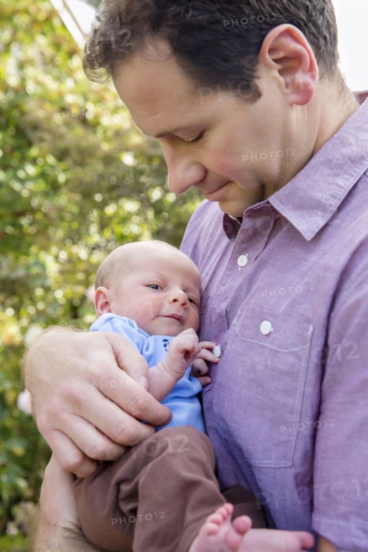 Father holding newborn son outdoors