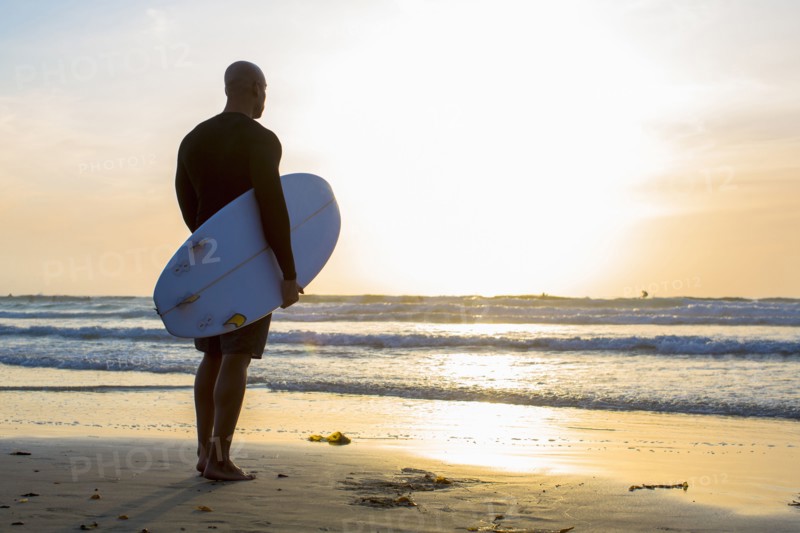 Mixed race man holding surfboard on beach