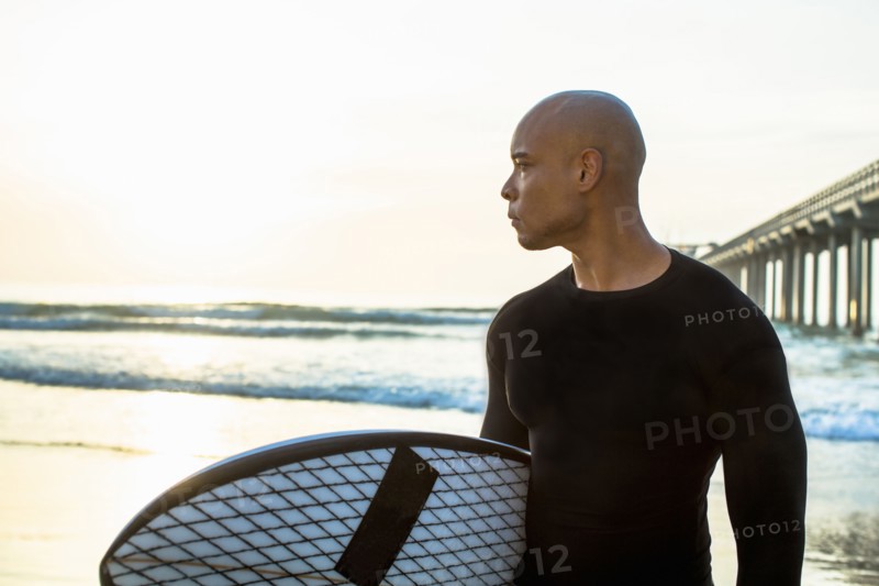 Mixed race man holding surfboard on beach