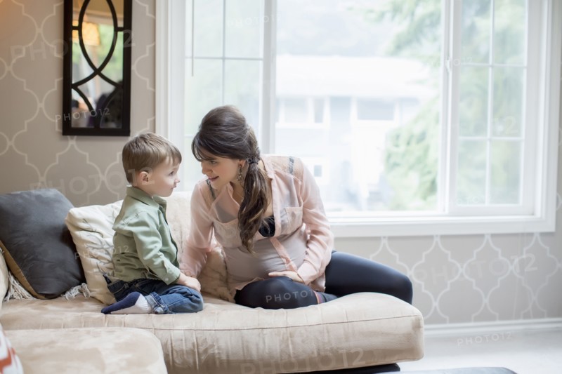 Pregnant Caucasian mother sitting with son in living room