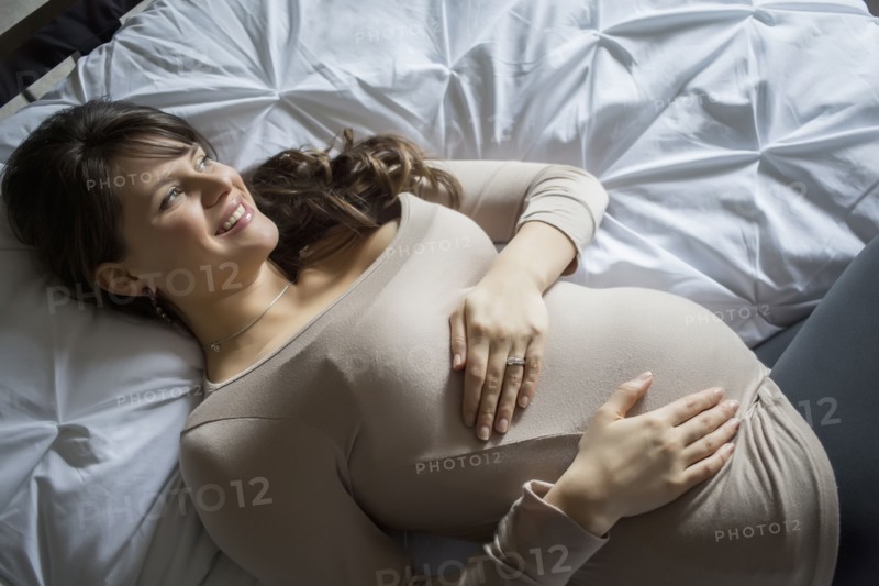 Pregnant Caucasian woman laying on bed