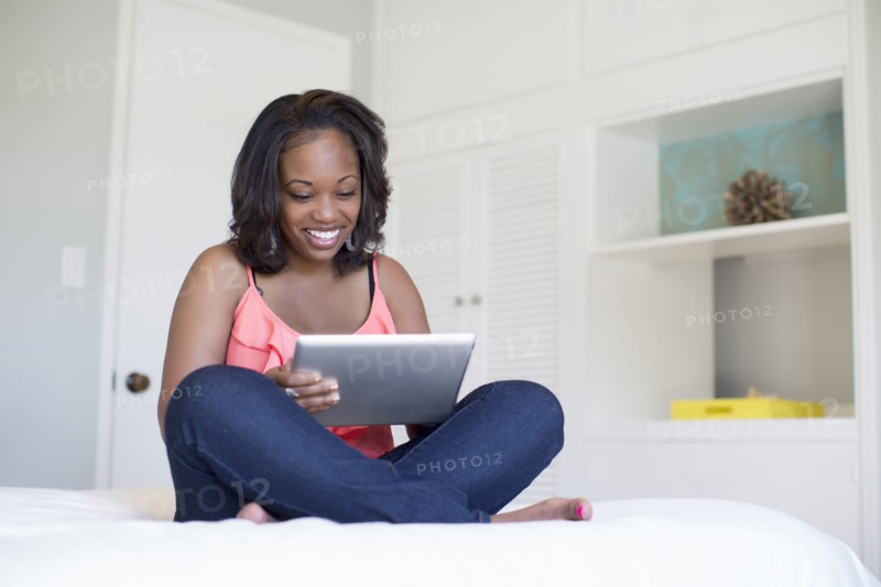 Woman using digital tablet on bed