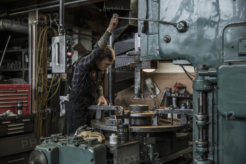 Caucasian man using machinery in metal shop