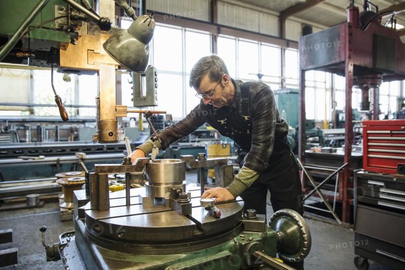 Caucasian man using machinery in metal shop