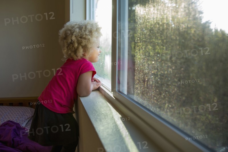 Mixed race girl looking out window