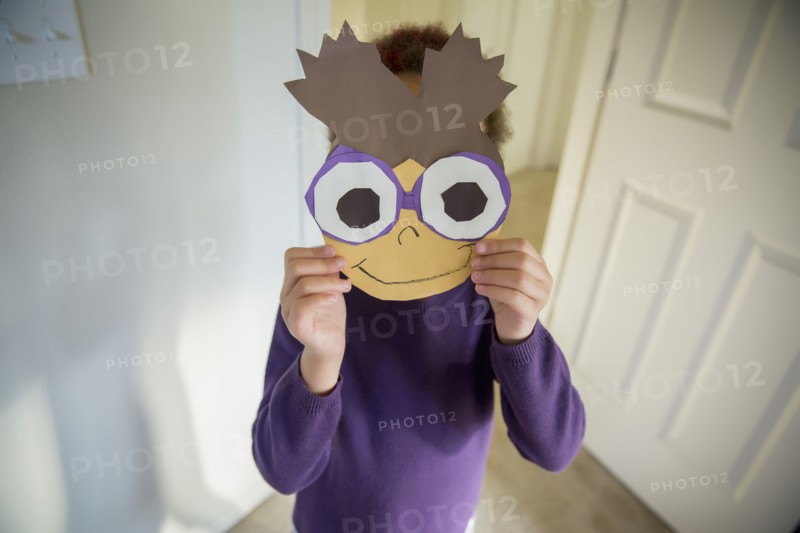 Mixed race girl holding mask over face