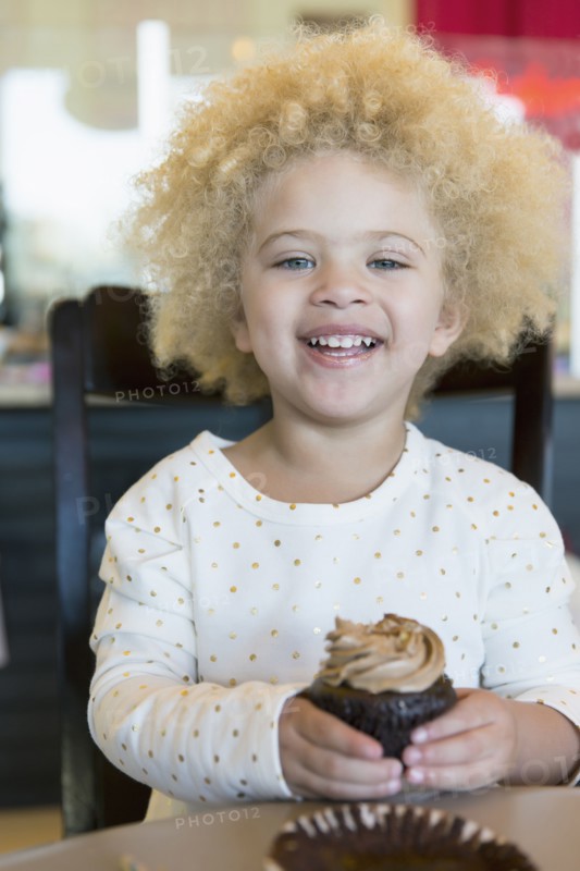 Mixed race girl having cupcake in bakery